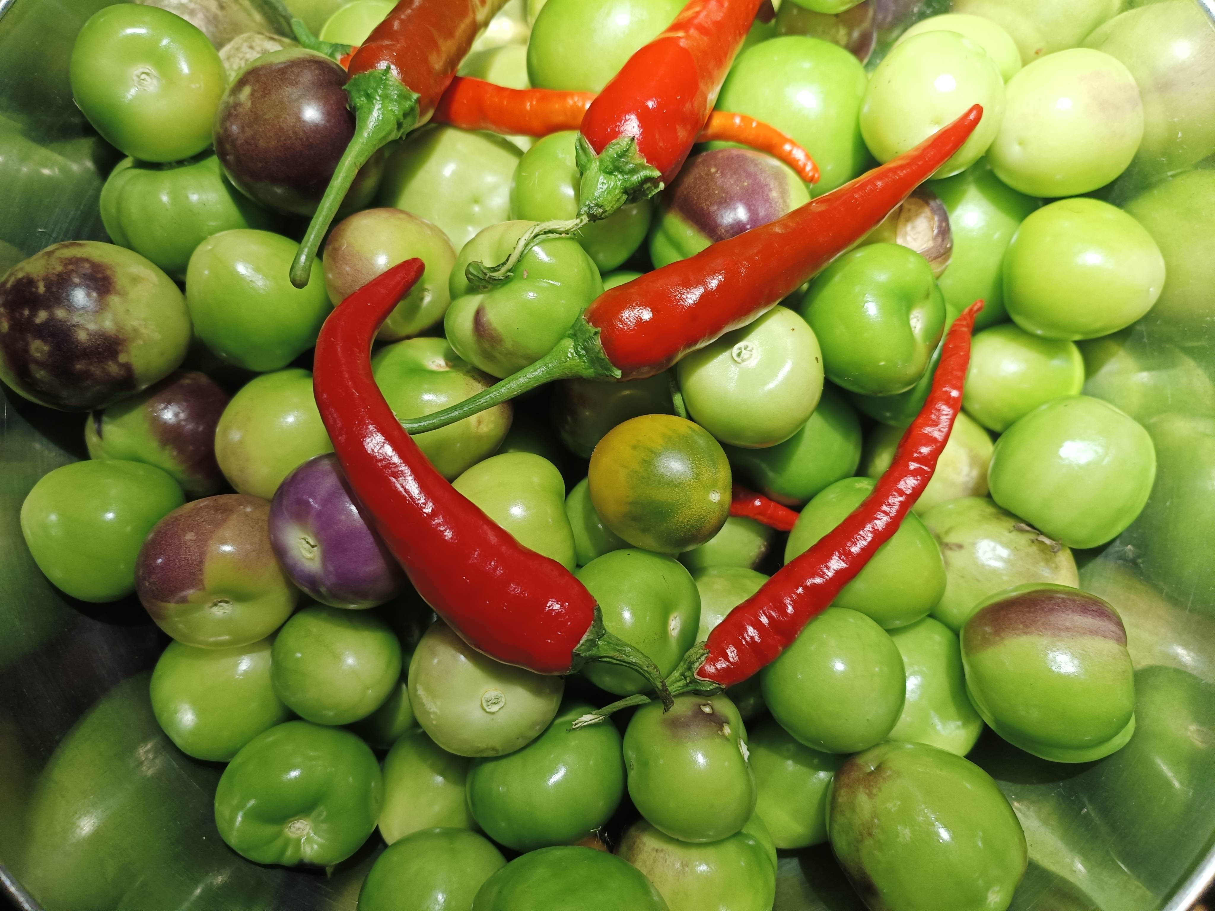 Grüne Tomaten mit roten Chili-Schoten