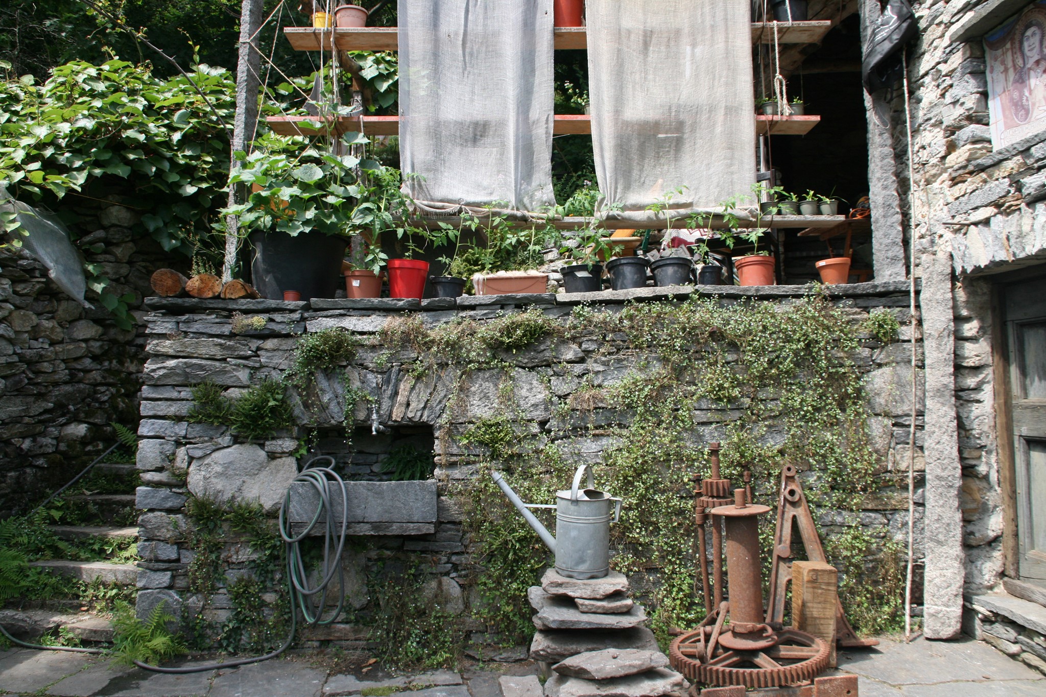 Rustikaler Innenhof mit traditioneller Steinarchitektur und Gartenwerkstatt